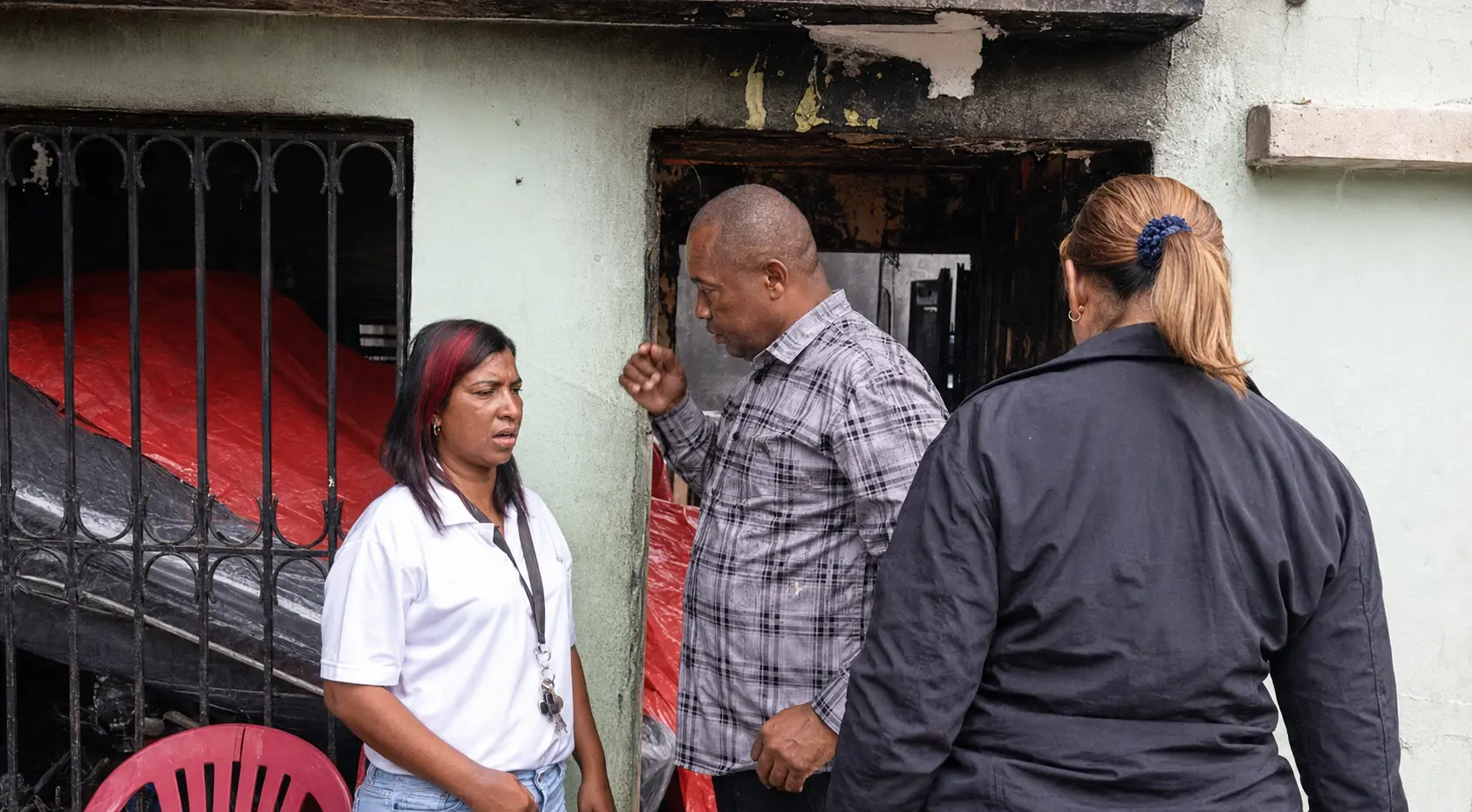 Ramón de los Santos conversa con una familia frente a una vivienda afectada por un incendio